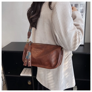 Vue détaillée du sac cylindrique marron avec sangle ethnique et pendentif à pompon