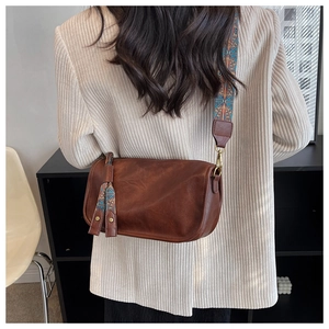 Détail du sac bandoulière vintage marron avec large sangle ethnique et cuir mat