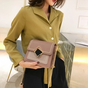 Sac bandoulière en cuir rose poudré avec broderie et chaîne dorée porté par mannequin