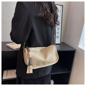 Détail d'un sac bandoulière en cuir beige avec foulard en soie sur un mannequin