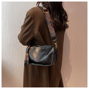 Détail du sac polochon noir en simili cuir avec bandoulière tissée de style ethnique