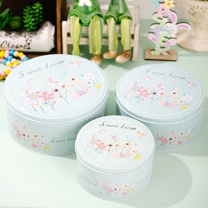 Détail de trois boîtes en fer vert pastel avec des motifs de lapins pour Pâques