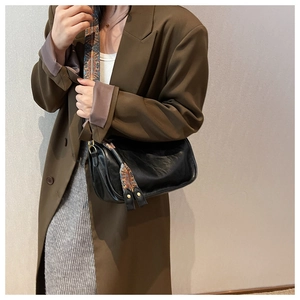 Détail du sac polochon noir avec large bandoulière brodée ethnique porté par un mannequin