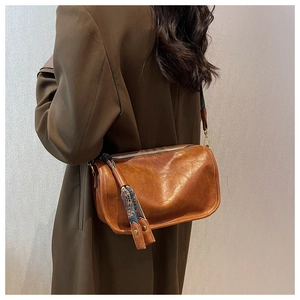 Détail d'un sac bandoulière en cuir marron avec sangle tissée ethnique porté par un mannequin