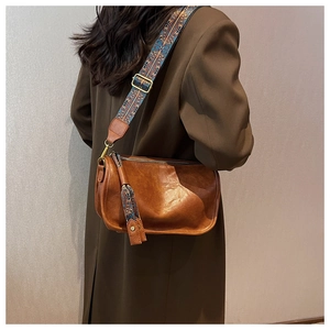 Sac bandoulière marron avec sangle ethnique porté sur un blazer marron foncé