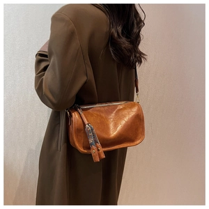 Détail du sac bandoulière en cuir marron avec pompon au motif ethnique vintage