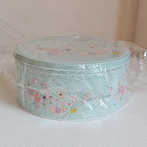 Détail d'une boîte de Pâques ronde avec motifs de lapin et fleurs sous film plastique