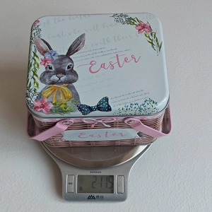 Close-up of Easter tin basket weighing 211.5g on a scale showing its metal construction