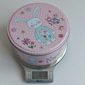 Vue détaillée d'une boîte en fer lapin de Pâques pesant 165,6 g sur une balance de cuisine