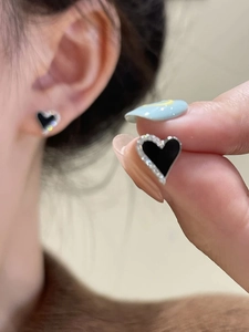 Detail showing asymmetric black heart earrings with sparkling rhinestones on the ear