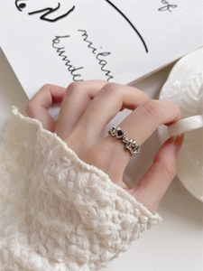 Close-up of a silver heart ring with a purple gemstone on a vintage artistic background