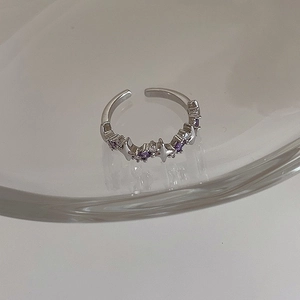 Macro detail of silver adjustable ring featuring purple and white starburst zircons
