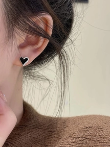 Elegant asymmetrical black heart stud earrings with sparkling crystals shown on ear