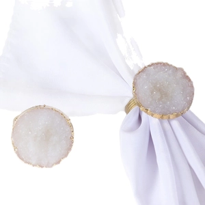 Set of two natural white crystal napkin rings with elegant golden edges on white fabric