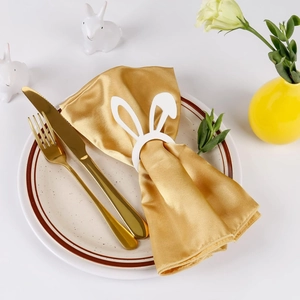 Rond de serviette en bois oreilles de lapin blanc avec serviette dorée sur table chic