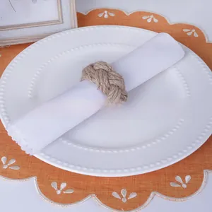 Close-up of handmade woven jute napkin ring with rustic knot design on white linen