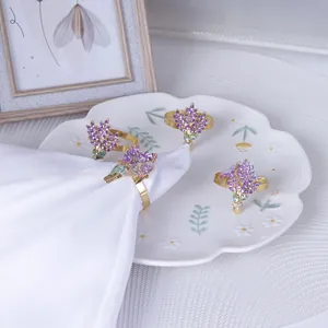 Détail de quatre ronds de serviette dorés avec cristaux violets sur une assiette fleurie