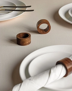 Close-up of handmade dark walnut wood napkin rings with natural grain on a ceramic plate
