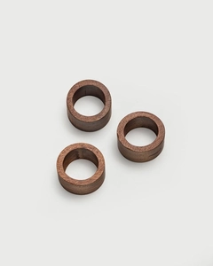 Close-up of three handmade dark walnut wood napkin rings with natural grain on gray background