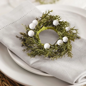 Christmas pine needle napkin ring with white berries on a table setting with plates