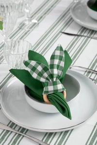 Detail of green plaid bunny ear napkin ring with light wood base on a dining set