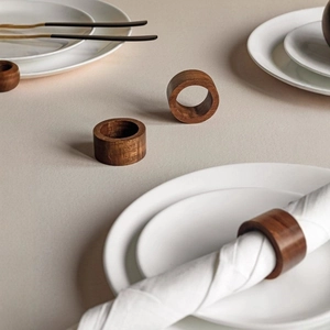Minimalist dark walnut wood napkin ring set with natural grain on white ceramic dinnerware