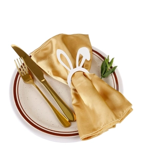 Rond de serviette oreilles de lapin blanc avec serviette en satin doré sur assiette