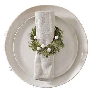 Cedar napkin ring with white berries and green pine needles on grey linen cloth