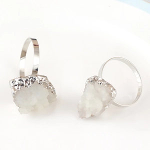 Detailed close-up of two silver metal napkin rings with natural white crystal clusters