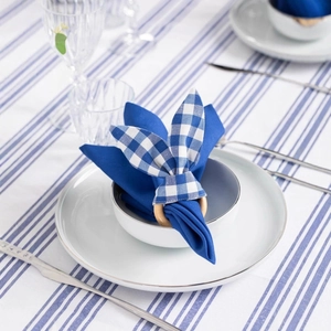 Easter rabbit ear wooden napkin ring with blue plaid fabric on a white ceramic plate