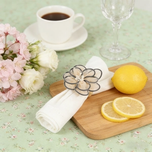 Exquisite organza flower napkin ring with bead center on a cream linen cloth