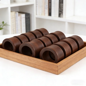 Set of 12 dark brown wooden napkin rings with smooth finish in a light wood tray