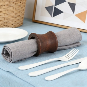 Close-up of a dark wooden napkin ring with a curved design on a grey linen napkin