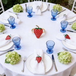 Close-up of a realistic strawberry napkin ring with red enamel on a white linen napkin