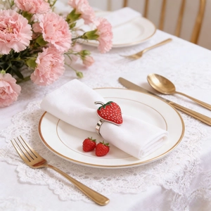 Realistic strawberry napkin ring with green leaves on a white linen napkin setting