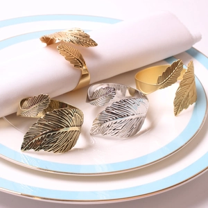 Elegant gold leaf napkin rings in various metal finishes on a white porcelain plate