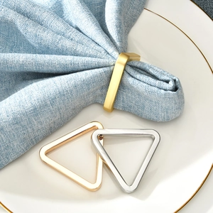 Modern geometric metal napkin rings in gold and silver finishes on a white plate