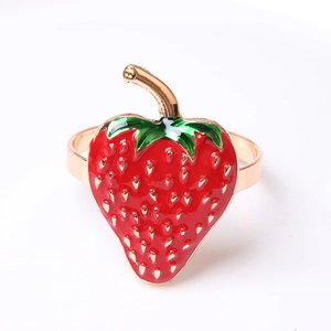 Close-up of strawberry napkin ring with red enamel finish and golden metal leaf detail