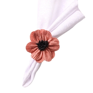 Fringed peach flower napkin ring with black bead center on white cotton linen napkin