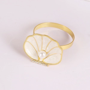 Rond de serviette coquillage doré avec émail blanc, perle et strass sur fond blanc épuré