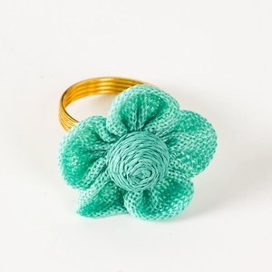 Dettaglio dell'anello portatovagliolo con fiore in lino verde menta e base in filo dorato