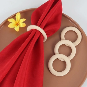 Macro detail of four natural wood napkin rings with red fabric napkin on a plate