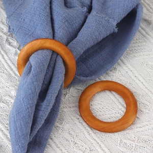 Detail view of two natural round wooden napkin rings on a white and blue textured cloth
