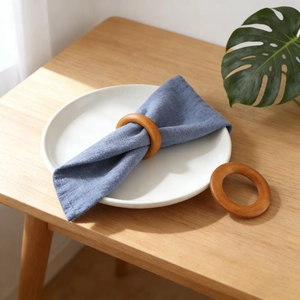 Natural wood napkin rings with round modern design on blue linen and white ceramic plate