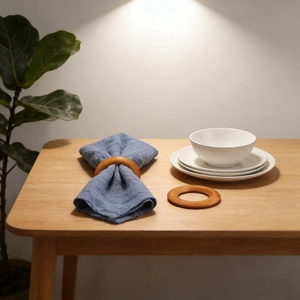 Natural wooden napkin rings set shown with blue cotton linens on a minimalist dining table