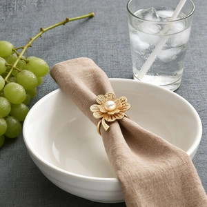 Detail of luxury gold flower napkin ring with a center pearl on a linen napkin