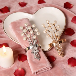 Portatovaglioli con rose e perle e fiocchi di strass su una tavola apparecchiata