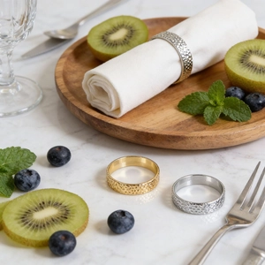 Detail view of gold and silver hammered metal napkin rings on a white napkin over a marble table