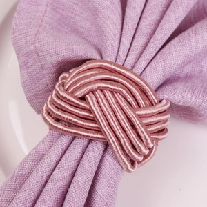 Rose gold woven napkin ring on purple linen napkin with elegant dinner table setup