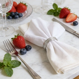 Detail of silver napkin ring with hammered texture on a white cloth napkin